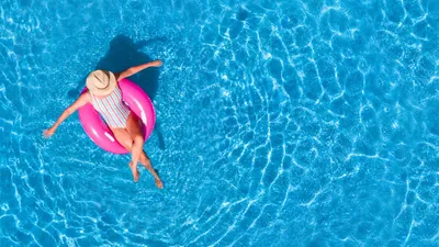 Pessoa em uma boia rosa numa piscina azul, imagem usada pela Accor na página da campanha